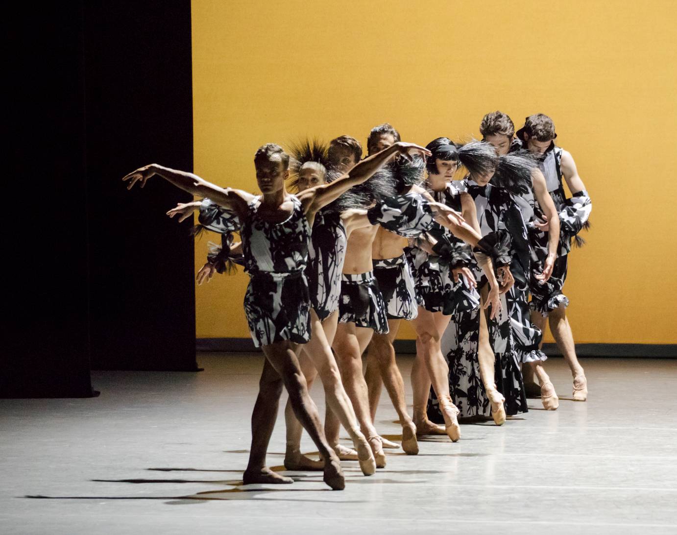 Eight dancers in a line that stretches from downstage to up